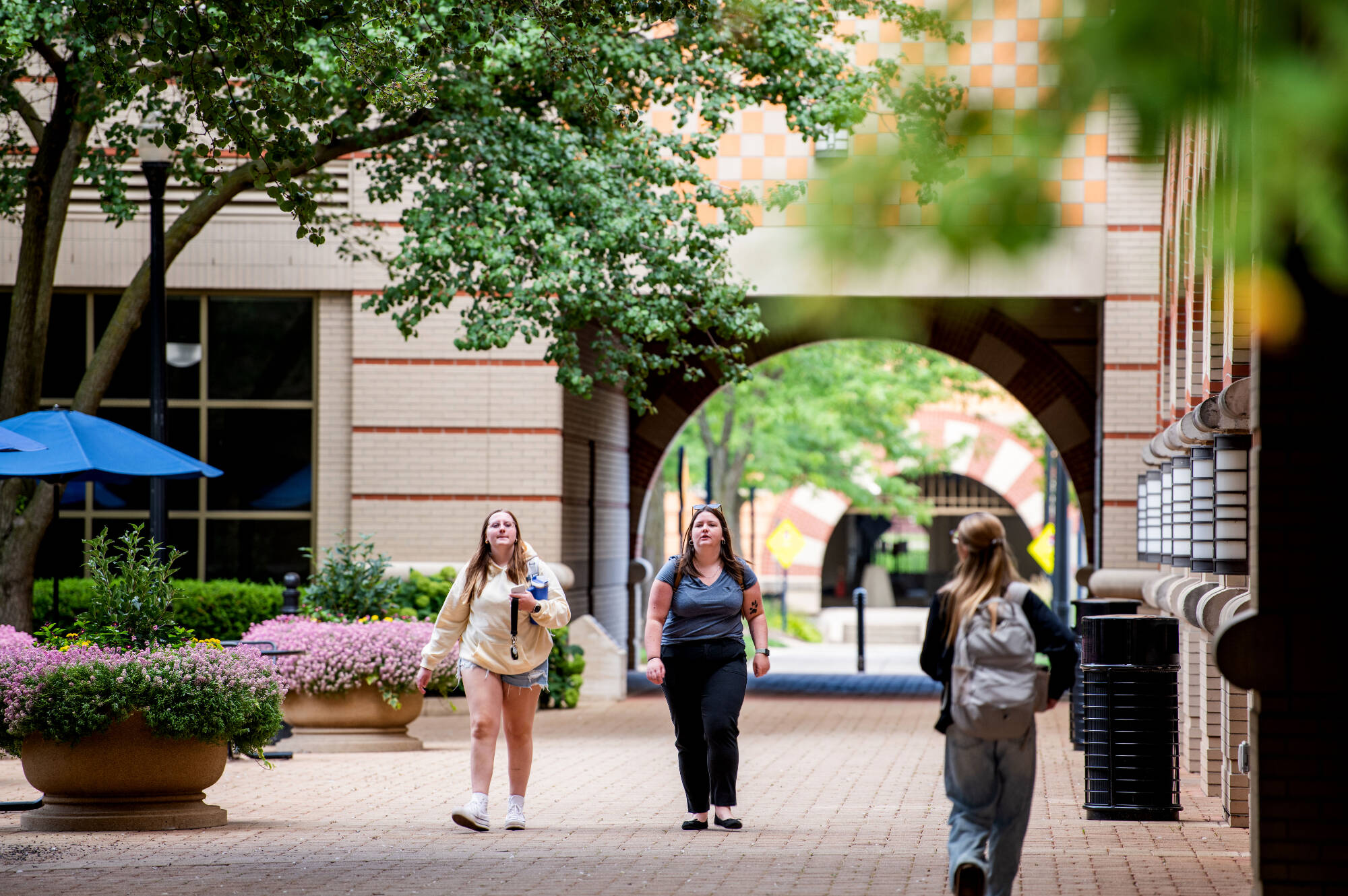 students walking under archways in Pew courtyard outside Devos